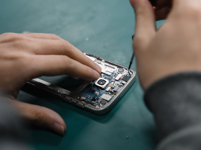 Technician performing ultrasonic cleaning on phone components